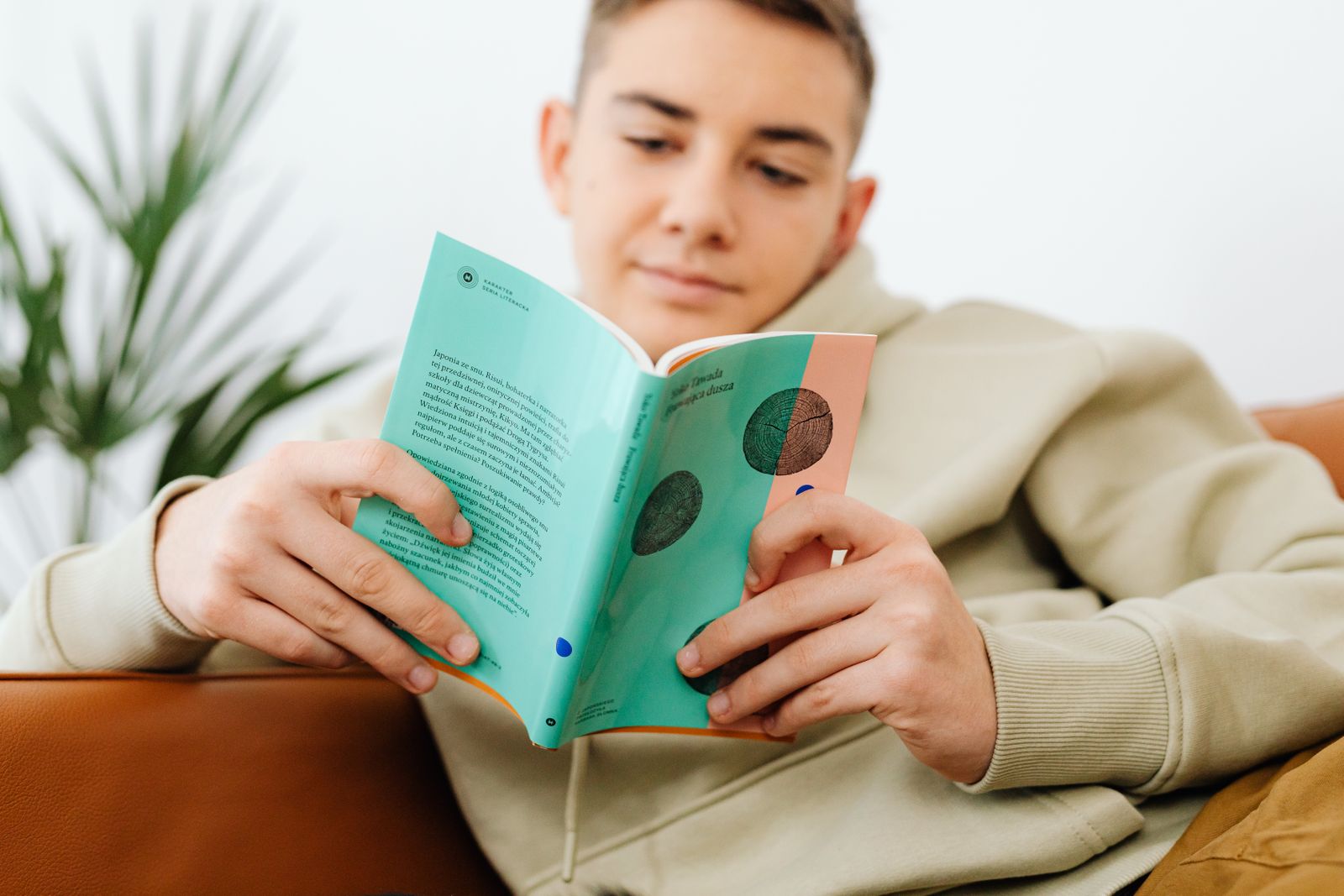Подросток спокойно читает книгу на диване